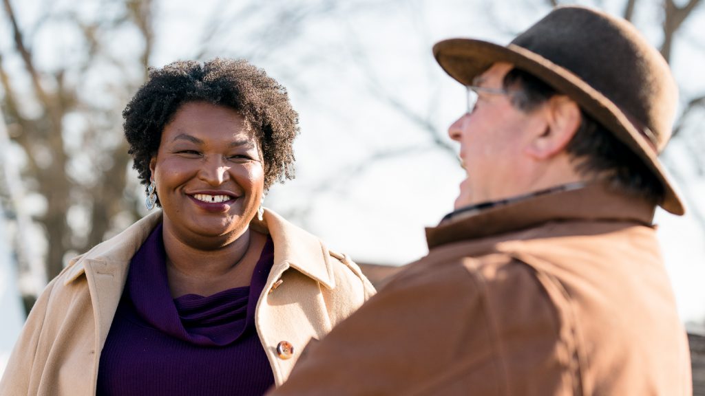 Photo of Stacey Abrams outside talking with a supporter.