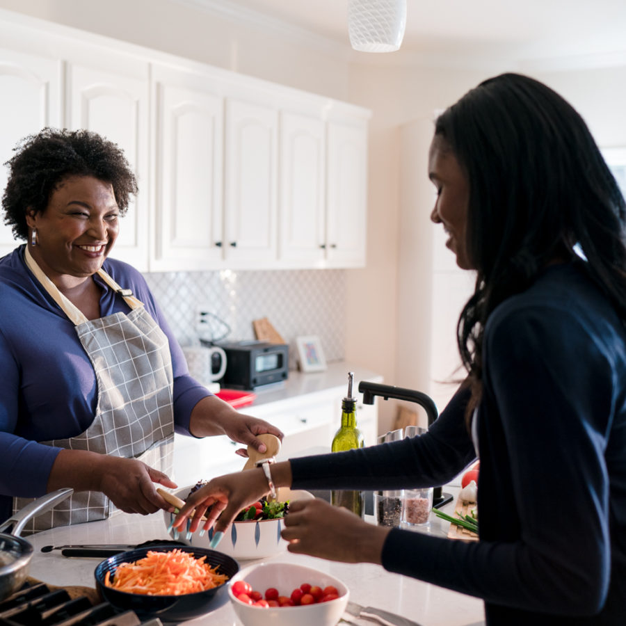 Stacey Abrams helping make food in a kitchen.